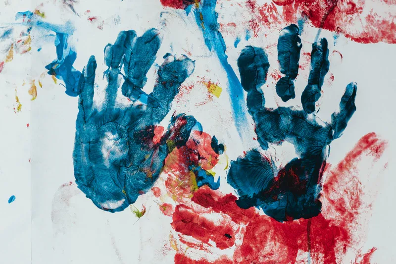 Painted hand prints on a white wall from the I Heart Art Studio.